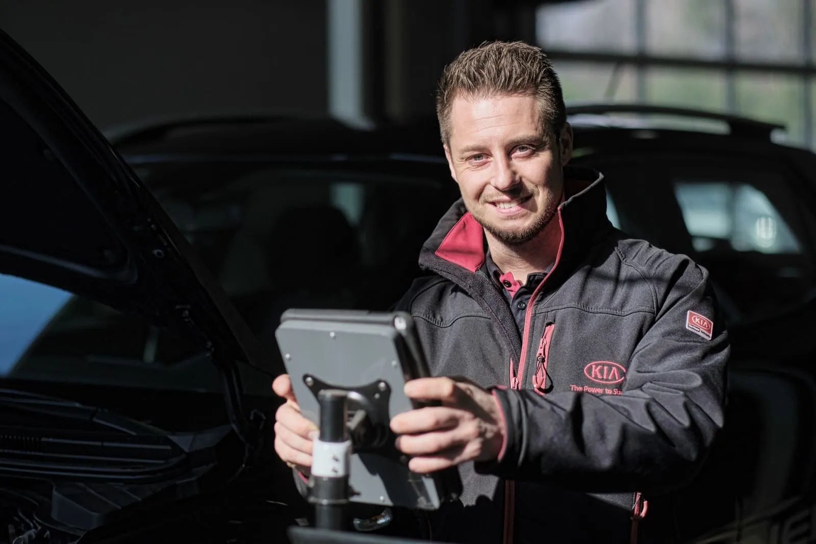 Techniker mit Diagnosegerät an einem Fahrzeug